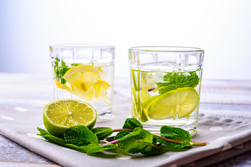 close-up of lemon and lime water on grey polka dot napkin on grey background