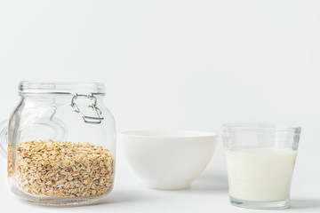 Glass of non-diary animal-free plant based milk rolled oats in reusable crystal jar bowl on white kitchen table. Healthy breakfast energy fitness concept