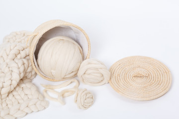 Basket with balls of Merino wool and plaid large knit on a white background.