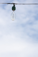 Fototapeta na wymiar The outdoor light bulb hanging on wire with blue sky background.