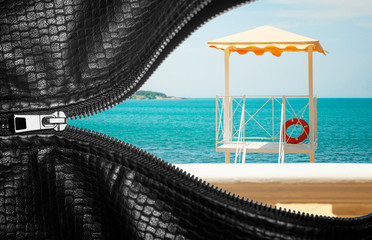 Sea beach with blue water and a bungalow fringed by a leather bag on a zip-fastener. Conceptual photo.