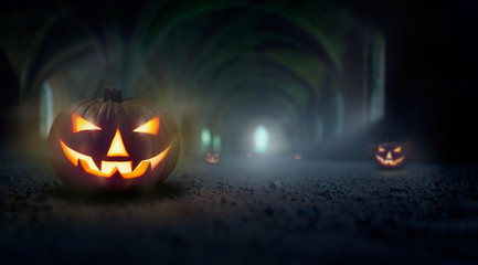 Jack O' Lanterns in a cold, misty and dark blue spooky ruins of an old church, monastery