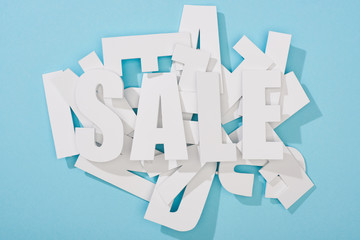 top view of white sale word on pile of letters on blue background