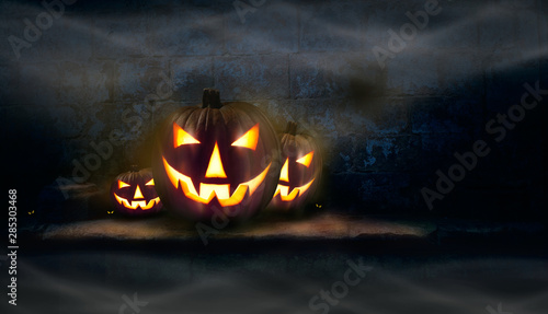 Three Jack O' Lanterns and spooky eyes on a stone plinth with mist hanging in the air.
