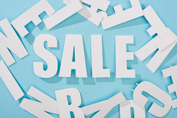 top view of white sale lettering among letters on blue background