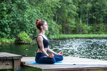 Yoga meditation  by Young yogi  girl  on the pier of a beautiful lake.  The concept of appeasement,  healthy lifestyle.