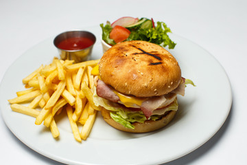 bacon burger with chicken cutlet, french fries, salad