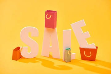 white sale lettering with shopping bags on bright orange background