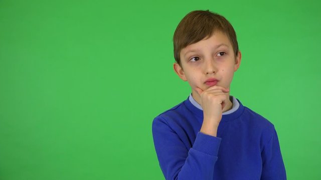 A young cute boy thinks about something - green screen studio