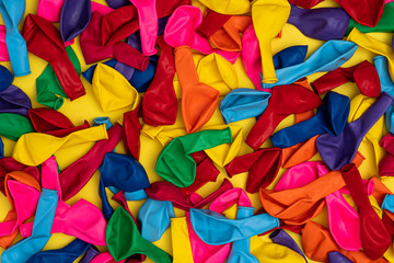 Fototapeta na wymiar Top view of deflated colorful balloons on yellow background
