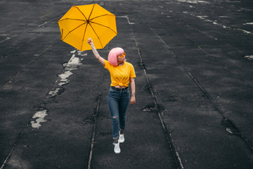 Teen influencer with yellow umbrella walking on street