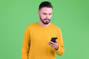 Portrait of young handsome bearded man using phone