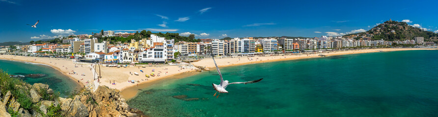 Coastline of the resort Blanes on the Costa Brava with azure sea, sand beach and seagulls, Spain.