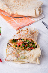international vegetarian  shawarma sandwich roll with vegetable and greens. served at white table. arabian and caucaisian cuisine. Healthy fast food. close up