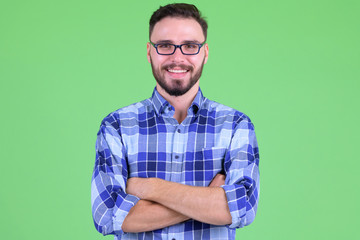 Happy young bearded hipster man smiling with arms crossed