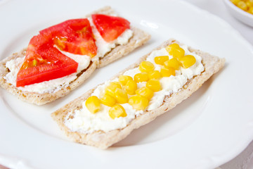 Homemade Crispbread toast with Cottage Cheese and green olives,slices of cabbage,tomatoes,corn,green pepper on cutting board on white concrete background.Healthy food concept,Top view.Flat Lay