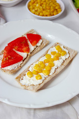 Homemade Crispbread toast with Cottage Cheese and green olives,slices of cabbage,tomatoes,corn,green pepper on cutting board on white concrete background.Healthy food concept,Top view.Flat Lay