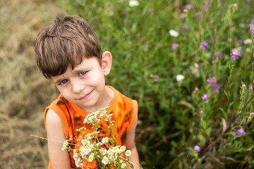Portrait of a young boy with a bouquet of wild flowers, cute guy smiling and collecting flowers in the park for a very loving mom