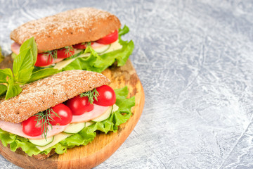 Sandwich with cheese, cucumber and Cherry Tomato on a wooden board. The sandwich is decorated with a lettuce leaf and cherry tomatoes.