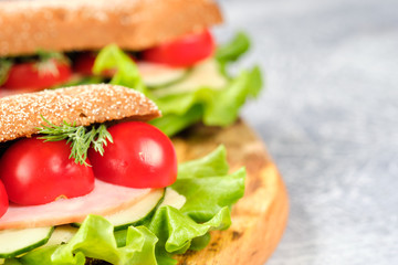 Sandwich with cheese, cucumber and Cherry Tomato on a wooden board. The sandwich is decorated with a lettuce leaf and cherry tomatoes.