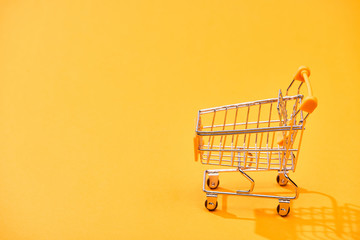 empty decorative shopping cart on bright orange background