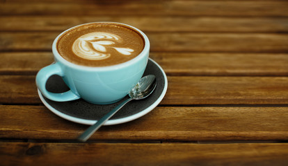 Cup of hot cappucino on the wooden table. Early morning breakfast