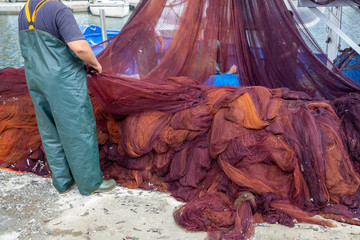Fisherman cleaning nets and spread on the ground