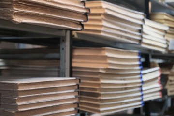 Blurred background. Bookshelves in the old library or museum archive room. Bundles of documents, books or newspapers. The concept of historical value and the desire for knowledge. Copy space.
