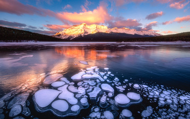 Frozen bubbles in Canadian Rockies. Photo was taken in Lake Minnewanka, Banff National Park. It's frozen bubble hunting season now but you don't have to drive hours all the way to Abraham Lake - obrazy, fototapety, plakaty