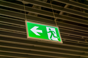 Emergency fire exit sign glowing green in the blacked out background at airport