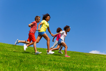 Four happy diverse looking children run on lawn