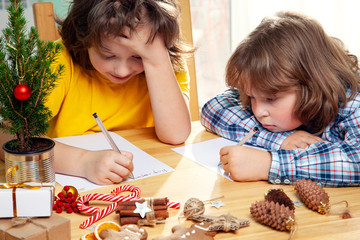 two Boys write a letter to Santa Claus. Near christmas tree. Merry Christmas and Happy Holidays