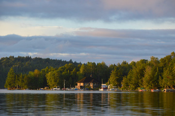 Marina on Saranac Lake bathed in the morning sunrise. The coastline and boats are reflected in the water and framed by the beautiful sky.