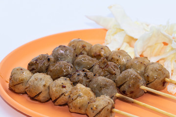 Grilled meatballs on a wooden stick with in orange plate isolate on white background.