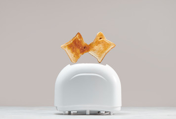 Roasted toast bread popping up of toaster with white wall, front view
