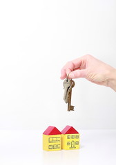 keys in hand representing property purchase with miniature toy block houses on table with white background and people body part stock photo