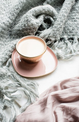 Beautiful enameled cup of coffee with pink silk and knitted blanket