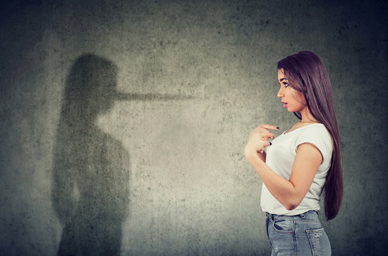 woman pointing at herself looking at a shadow with long nose of a liar.