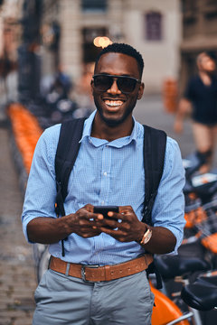 Handsome American Tourist Is Checkin His Mobile Phone On The Busy Street In The City.