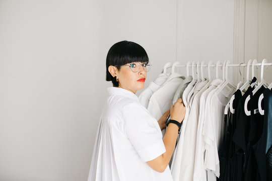 Stylish designer exploring clothes on rack