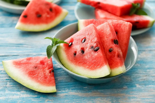 Close-up of fresh red watermelon slices in blue plate on an blue rustic wooden background.