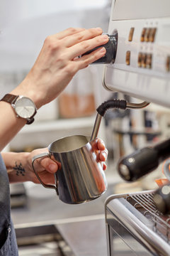 Barista whips milk foam for making cappuccino in the coffee mach