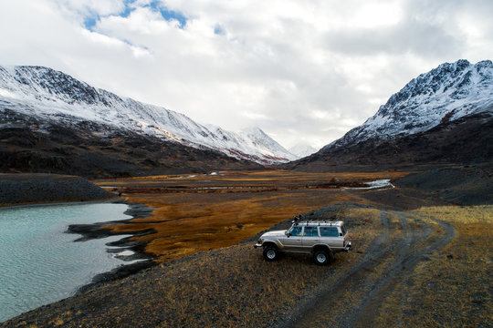 a top view of a very beautiful valley through which the river flows, forests grow around, a steppe follows them and huge snowy mountains stand behind it