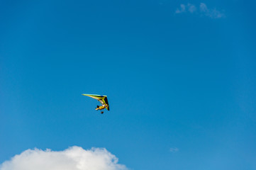 Man on a hang gliding in a blue sky with clouds