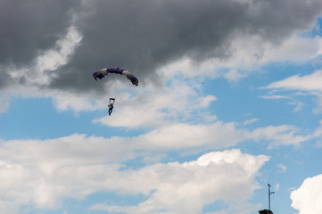 Fototapeta na wymiar Man on a parachute in a blue sky with clouds