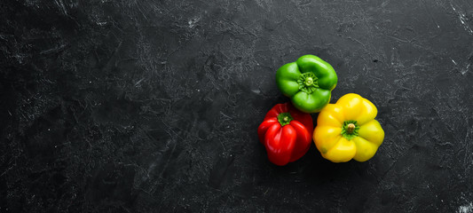 Fresh colored paprika on black stone background. Top view. Free copy space.