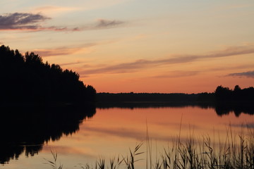 Reflected in the water of the forest lake late sunset summer evening. Valdai national Park.