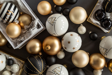 Black, white and gold Christmas ornaments on grey background