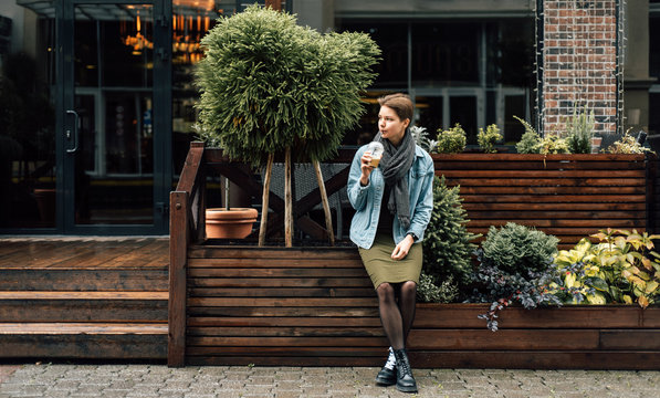 Stylish woman drinking near cafe