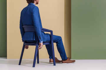 Rear view of man in blue suit sitting in a chair